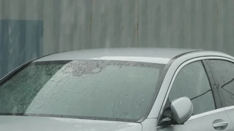 Heavy rain drops falling on a silver car roof outdoors. Video stock 338365424