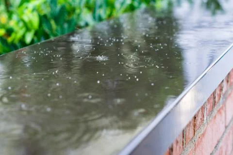 Heavy rain drops falling on a wall in the city street. Stock Photos