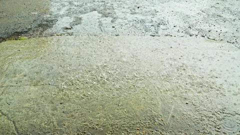 Heavy rain drops falling on a wet concrete and asphalt surface outdoors Stock Footage 340334912