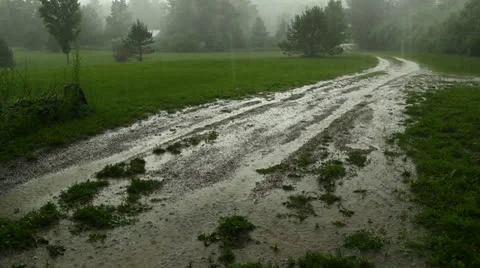 Heavy rain eroding a muddy driveway Stock Footage 26110428