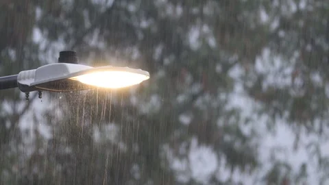 Heavy rain fall and raindrops slide along the bright lamp light on rainy day.4K. Stock Footage 260238591
