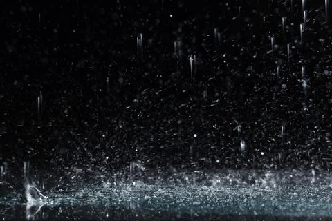 Heavy rain falling down on ground against dark background Stockfoto's