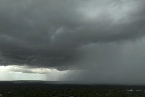 Heavy rain falling down from stormy clouds during thunderstorm on dark sky. M Stock Photos