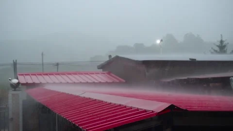 Heavy Rain Falling Over Red Metal Roofs In A Rural Village Setting Video stock 341963627
