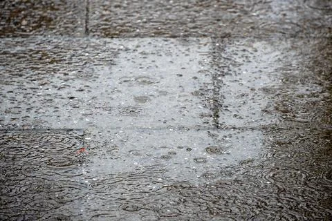 Heavy rain falling on paved area for use as a background texture Stock Photos