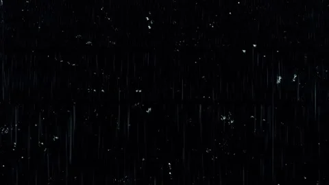 Heavy rain falling rapidly against a dark black background with water droplets Stock Footage 338997656