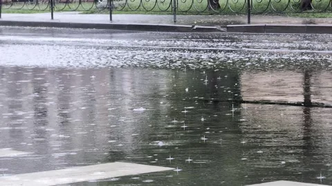 Heavy rain falling on street creating large puddles and ripples with car driving Stockbeeldmateriaal 342230596