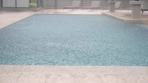 Heavy rain falling into swimming pool Stockbeeldmateriaal 158465834