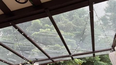 Heavy rain falling on transparent protective cover above garden terrace Stock Footage 336685989