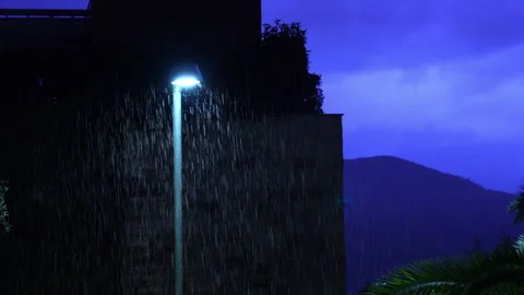 Heavy rain falling under a street lamp at night Stock Footage 346194408