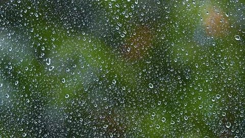 Heavy rain falling on window.green bokeh in background from trees.spring rain Stock Footage 133002242