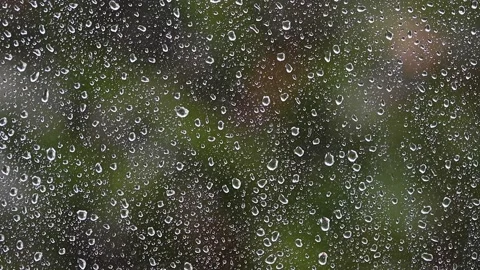 Heavy rain falling on window.green bokeh in background from trees.spring rain Stock Footage 133002328