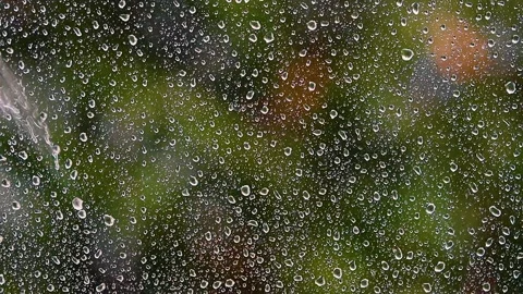 Heavy rain falling on window.green bokeh in background from trees.spring rain Stock Footage 133002338