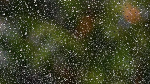 Heavy rain falling on window.green bokeh in background from trees.spring rain Stock Footage 133002371