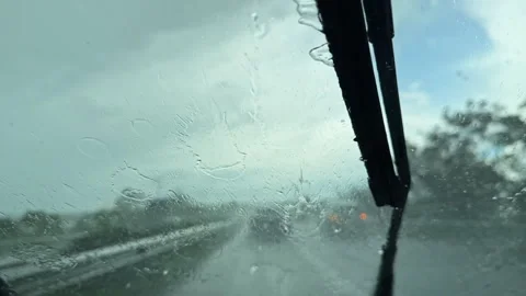 Heavy rain falls on a highway as seen from a car windshield with wipers in Stock Footage 337891610
