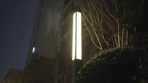Heavy Rain Falls at Night Illuminating Droplets Near Modern Building Video stock 337409288