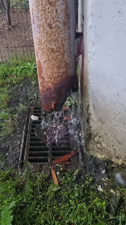 Heavy rain flowing from a broken and rusty metal downspout.  Stock Footage 327158064