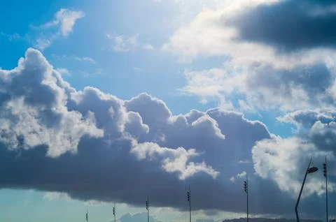 Heavy rain heaps clouds with dense dark sides against the blue sky and sunlig Stock Photos