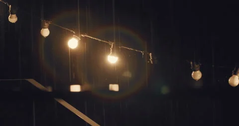Heavy rain at night with fairy string lights hunging on backyard Stock Footage 224878577