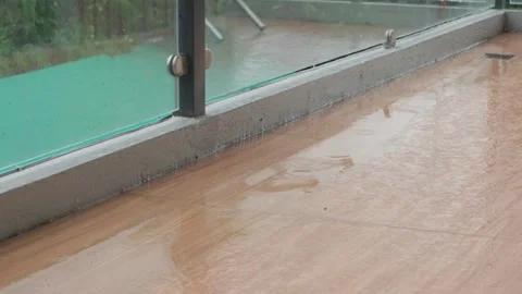 Heavy Rain Pouring and Pooling on a Modern Tiled Balcony with Glass Railing Stock Footage 339115188