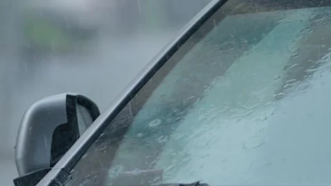 Heavy rain pours on car windshield in urban setting during late afternoon Stock Footage 345203214