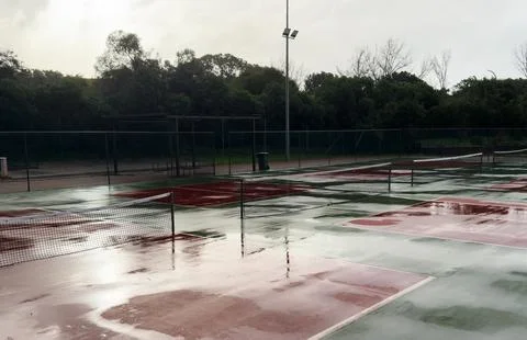 Heavy rain pours down on empty tennis courts, soaking the surface and disto.. 스톡 사진