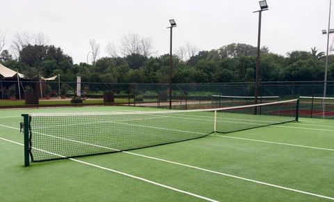 Heavy rain pours down on empty tennis courts, soaking the surface and disto.. Foto stock