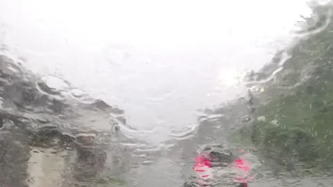 Heavy rain pours down over a city street, viewed through a car windshield Stock Footage 335066237