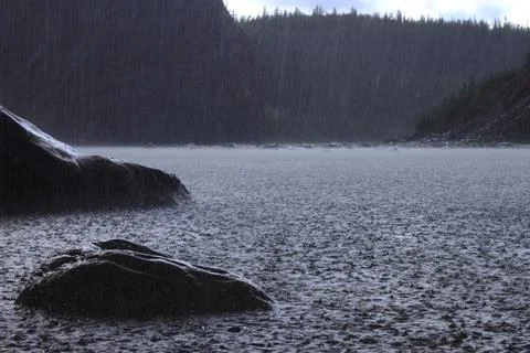 Heavy rain on the river surface and wet black stones Foto stock