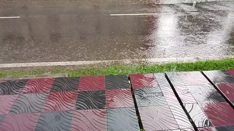 Heavy rain showers falling on paved city street sidewalk close up view 動画素材 337230069