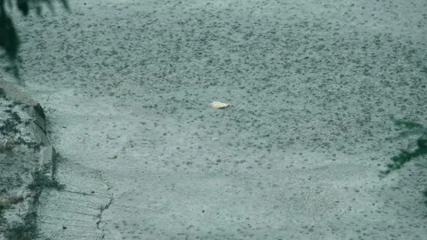 Heavy rain on the sidewalk. Raindrops fall on the road. Slow motion 库存影片 240440047
