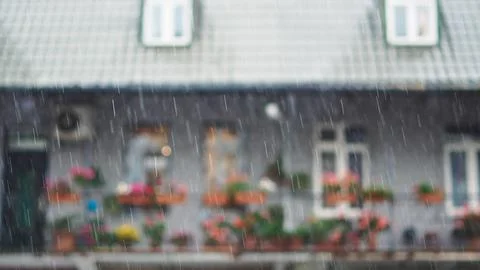 Heavy rain streaks in sharp focus against a beautifully blurred house backgro Stock Photos