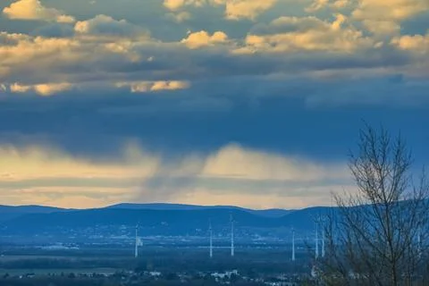 Heavy rain under clouds during sundown in a landscape with windmills Stock Photos