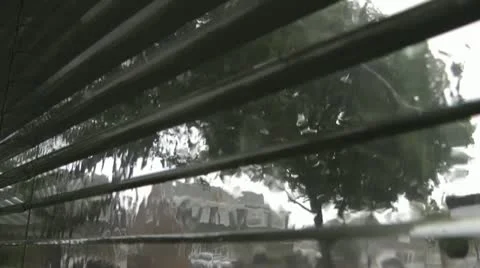 Heavy rain on window during a thunderstorm, looking through Venetian blinds 動画素材 14706686