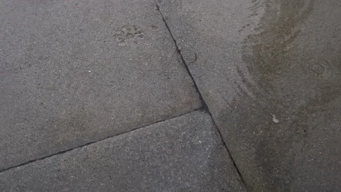 Heavy raindrops falling and splashing in puddles on sidewalk Stock Footage 118991152