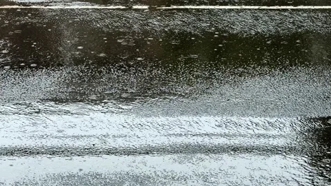 Heavy rainfall hitting wet asphalt road surface on empty urban street slomo Stock Footage 312382250
