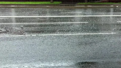Heavy rainfall hitting wet asphalt road surface on empty urban street Stock Footage 312382260