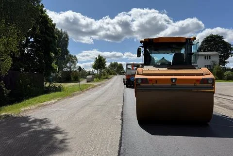 Heavy road roller compacting new asphalt on a rural road concept of road cons Foto stock