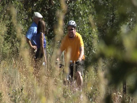 Heavy-set mountain biker passes couple hiking on trail, Park City, UT. Stock Footage 99119651
