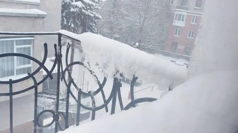 Heavy Snow Blankets Balcony Railing with Urban Rooftops in Background Stock Footage 326317328