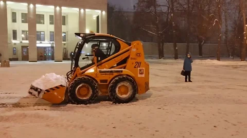 Heavy snow removal in progress in city square, featuring yellow maintenance Stockbeeldmateriaal 327163522