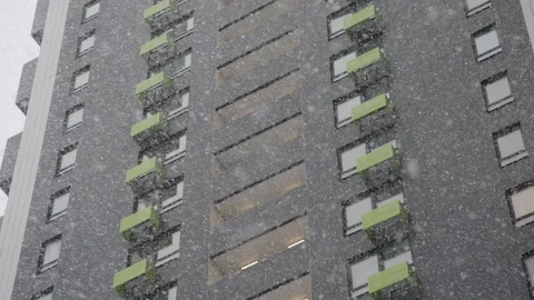 Heavy snow is slowly falling against the background of a multistory building Stock Footage 127789155