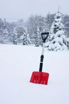 Heavy snowfall, Winter concept. A distinctive red shovel stuck in white  Stock Photos