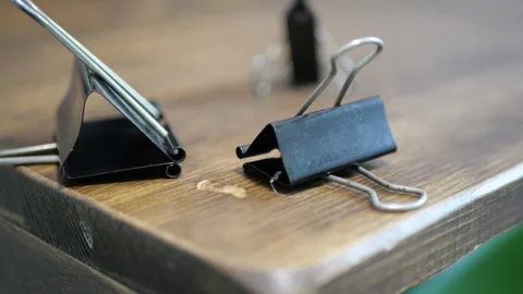 Heavy Steel Spring Clips Falling on Textured Wooden Desk with Sharp Metallic Video stock 321528559
