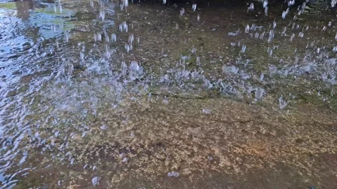 Heavy summer rain drops falling on concrete ground creating liquid ripples .. Stock Footage 344994033