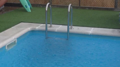Heavy summer rain falling on the turquoise water of a swimming pool creatin.. Stock Footage 341755172