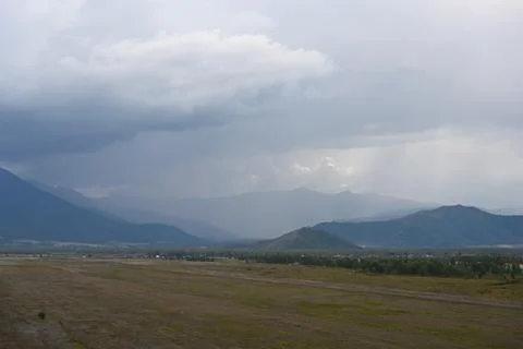 Heavy thunder clouds floating over the valley and mountains Stock Photos