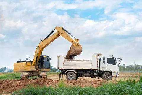 Heavy track excavator loading earth into a dumper truck for site preparatio.. Stock Photos