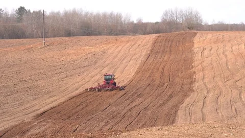 A heavy tracked tractor plows and buries a field in early spring, a plowed field Stock Footage 156076330