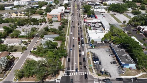 Heavy traffic moves along divided street lined with commercial buildings in Stock Footage 340192232